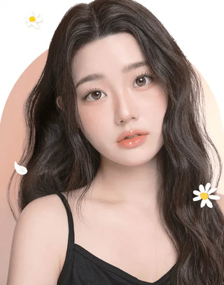 A young woman with long, wavy dark hair and clear skin poses against a soft gradient background, wearing i-Girl One Pick Becca Azuki Brown contact lenses by i-Girl. White illustrated daisies surround her neutral expression and black top.