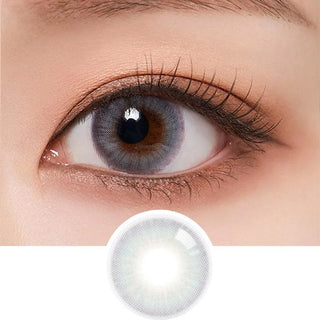 A close-up of a person's dark eyes wearing Olola Blow Midnight Grey contact lenses by Olola, showing the detailed lens design below the eye. The eye features long lashes, natural makeup, and supports myopia prescription.