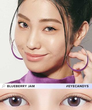 A woman with long dark hair, large purple hoop earrings, and a purple top smiles at the camera. At the bottom, her eyes feature N's Collection Blueberry Jam Violet (10pk) contacts by N's Collection.