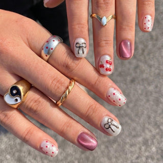 Hand wearing EyeCandys Cherry Bomb press on nails featuring 3D cherries, red polka dots, and cherry red glitter cat eye nails.
