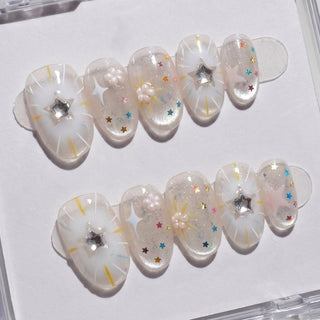 Constellation Prize Press-On Nails by EyeCandys feature a translucent base with white starbursts, colorful star confetti, rhinestones, pearls, and pink 3D stars—perfect for Y2K nail art fans and beautifully displayed on a white background.