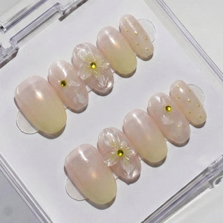 The Daisy Does It Press-On Nails by EyeCandys feature handmade, pearly pink nails with 3D translucent flowers and yellow bead accents for a spring-inspired, salon-quality look—beautifully displayed in a clear case.