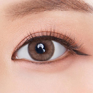 A close-up of a brown eye wearing Olola Dearsome Milk Brown color contact lenses by Olola, with accentuated lashes and softly blended brown eyeshadow. Suitable for both myopia prescription and non-prescription wearers.