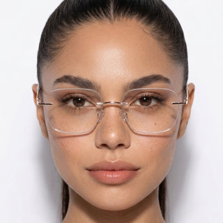 A woman with smooth, pulled-back dark hair wears EyeCandys Dusk Rimless Rectangular minimalist eyewear. She looks directly at the camera against a plain white background, with a neutral expression and clear skin.
