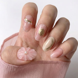 Close up hand showcasing EyeCandys En Rose press on nails with romantic pink tones, gold rose embossment, and pearl floral accents.