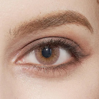 A close-up of a person's brown eye with natural makeup, detailed brow hairs, and smooth skin, wearing EyeCandys Attitude Glitter Pink (1 PAIR) lenses by EyeCandys for enhanced comfort and style.