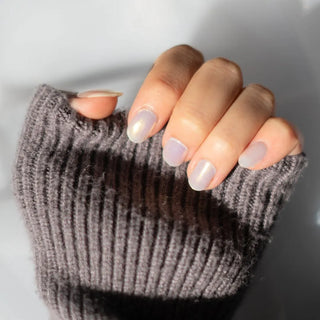 Model's hand showcasing EyeCandys Fiji Girlie Gel Nail Stickers. These iridescent white stickers offer a shimmering, elegant finish, providing a glossy, long-lasting manicure with minimal effort. The soft, radiant hue adds a touch of sophistication and style to any look.