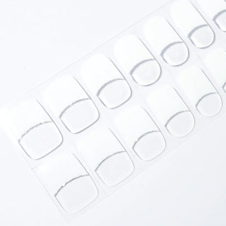 Angled image of semi-cured gel nail stickers in the design 'French Girlie,' featuring a classic white tip and transparent base with a delicate silver glitter tip for an elegant French manicure look.