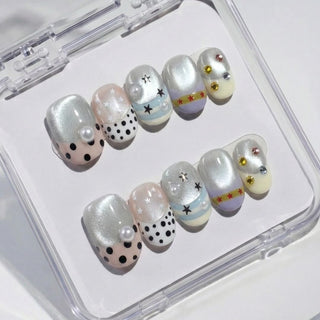 Short oval press on nails Headliner with silver shimmer nails, multicolor rhinestones, star patterns, and polka dot pearl details for a festival look.