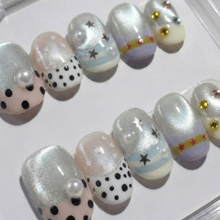 Headliner press on nails by EyeCandys featuring silver shimmer base, rhinestone clusters, star motifs, polka dot pearl accent, and bold festival nail art.