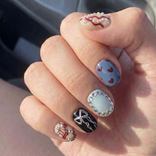 EyeCandys’ Heartbreak Hotel Press-On Nails feature five unique salon gel designs: plaid, black with a silver bow, pale blue with silver studs, blue with red hearts, and beige with a pearl border and red squiggle.