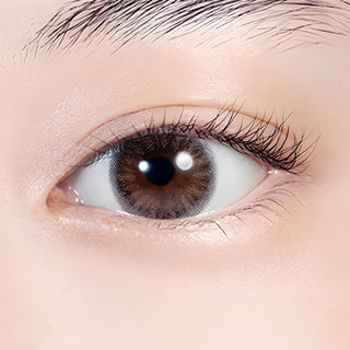 Close-up of an eye wearing Lilmoon Monthly Flamingo prescription and non-prescription colored contact lenses. Soft pink and sheer gray circle lenses with a two-tone gradient create a glossy, romantic eye look while naturally enhancing dark brown eyes. Monthly Japanese colored contacts with a delicate blush undertone, smoky halo, natural enlargement effect, and comfortable everyday wear.
