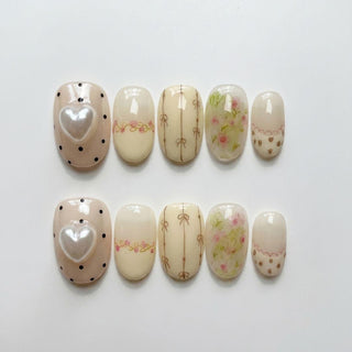Little Bea Press-On Nails by EyeCandys feature pastel, cottagecore-inspired designs: beige with silver hearts and black dots, pale yellow with pink bows, floral patterns, and scalloped edges adorned with small hearts.