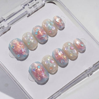 EyeCandys Love Tomorrow Press-On Nails feature handmade pastel, iridescent designs with swirls, pearls, and gems—beautifully arranged in a clear plastic case for an instant salon-quality gel manicure at home.