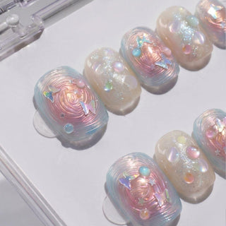 EyeCandys Love Tomorrow Press-On Nails feature handmade pastel, iridescent, and pearlescent designs with swirls, 3D gems, metallic stars and hearts on a white base for an easy salon-quality gel manicure at home.