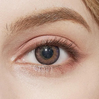 A close-up of an eye wearing NEO Vision Cosmo Violet circle lenses by NEO Vision, featuring a violet tone with a central mesh pattern, surrounded by natural skin and a well-groomed eyebrow.