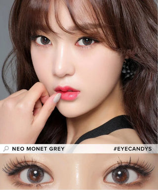 A woman with wavy brown hair and flawless skin models her makeup and NEO Vision Monet Grey (Custom Toric for Astigmatism) contacts. A close-up shows the striking lenses. Text reads “NEO VISION MONET GREY,” “#EYECANDYS,” and highlights astigmatism-friendly circle lenses.