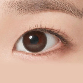 Close-up of a person's right eye with a brown iris, long lashes, and a well-groomed brow. Smooth, fair skin is enhanced by NEO Vision Neoism Coco Brown (50pk) contact lenses for a natural look.