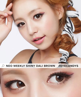 A woman with styled light brown hair and flawless makeup wears NEO Vision Weekly Shiny Dali Brown (12pk) lenses. A close-up highlights her shiny weekly disposables. Text: "Neo Weekly Shiny Dali Brown #eyecandys".