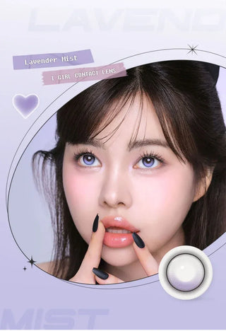 A woman with long dark hair and glossy lips wears i-Girl One Pick Balance Lavender Mist Purple contacts by i-Girl. She looks upward, showing pink blush and black nails. "Lavender Mist" appears in decorative text on a pastel background.