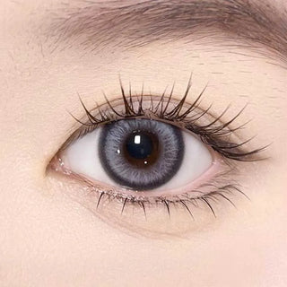 A close-up of a human eye with long lashes wearing Olola Meow Vivid Burman Grey color contacts by Olola, highlighting detailed iris patterns and smooth skin—ideal grey contacts for dark eyes.