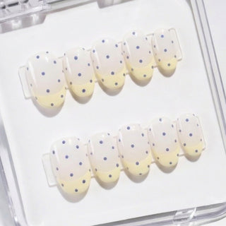 EyeCandys Sunday Dots press on nails featuring pastel yellow French tips and scattered periwinkle dots for a fresh, playful salon quality manicure.
