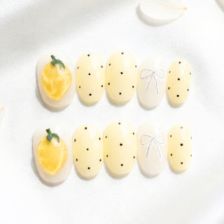 Limoncello press on nails by EyeCandys featuring pastel yellow base with 3D sculpted lemons, polka dots, bows, and gemstone accents in a playful summer nail set.