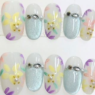 Floreline press on nails by EyeCandys featuring sheer milky base with hand painted pastel floral nail art in yellow, lavender, peach, and mint tones.