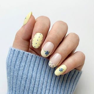 Hand wearing EyeCandys Blueberry Tart press on nails featuring cream and blush base with blueberry clusters, green leaves, and blue polka dots.