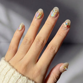 Stylish hand wearing Eyecandys Miraflores press on nails featuring iridescent chrome nails, delicate floral accents, and sculpted 3D flower design.