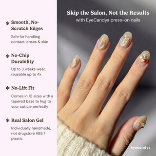 Hand displaying Eyecandys Miraflores press on nails with aurora shimmer, jelly base, gold wire floral art, and pastel flower embellishment.