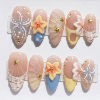 Shell Yeah press on nails by EyeCandys featuring sandy nude base with 3D conch shell, starfish flower, pearl accents, and ocean inspired nail art.