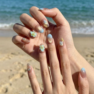 Close up hand showcasing Eyecandys Lei’d Back press on nails with tropical floral design, sculpted flowers, and soft sunset ombre gradient.