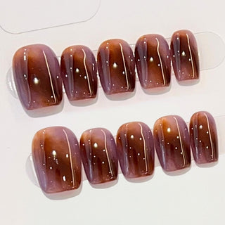 Close-up of EyeCandys Night Plum press on nails on a white background featuring a marbled plum tone with warm auburn depth, dark polished and striking design.