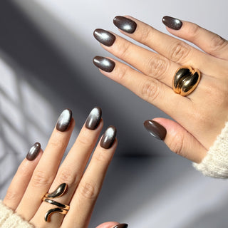 Hand wearing EyeCandys Midnight Cocoa press on nails featuring deep chocolate brown cat-eye design with cool blue-grey shimmer and magnetic glow.