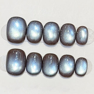 Close-up of EyeCandys Midnight Cocoa press on nails on a white background featuring deep chocolate brown cat-eye design with cool blue-grey shimmer and dimensional magnetic glow.