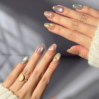 Hand wearing EyeCandys Star Script press on nails with sunset cat-eye gradient in peach, blush, and gold with sculpted star details.