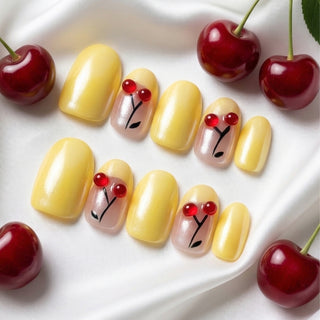 Close-up of EyeCandys Cherry Picnic press on nails on a white background featuring pastel yellow base with chrome finish, French tips, and sculpted cherry accents.