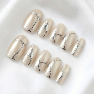 Close-up of EyeCandys In the Lines press on nails featuring soft white cat-eye base with pearly shimmer, delicate silver line details, and subtle gem accents on a white background.