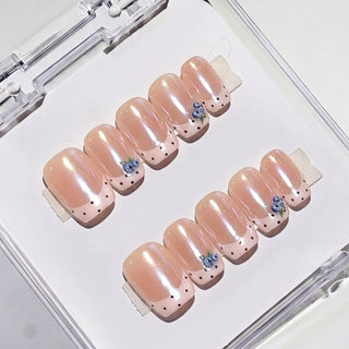 Close-up of Eyecandys Berry French reusable press-on nails showcasing pastel pink French tips, delicate black pin dots, and hand-painted blueberry nail art.