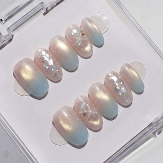 EyeCandys Pearl Jam Press-On Nails are glossy pale pink press-ons with a subtle iridescent sheen, white glitter accents, and a 3D bow for a chic pearl look, elegantly displayed in a clear case.