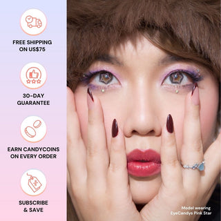 Close-up of a model with dramatic makeup wearing EyeCandys Pink Star pastel contacts in pink star shapes, hands framing her face. Left side highlights EyeCandys perks: free shipping over $75, 30-day guarantee, points on orders, and subscribe & save.