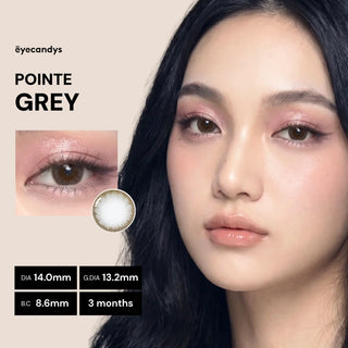 A woman with long dark hair wears EyeCandys Pink Label Pointe Grey contact lenses. A close-up of her eye appears on the left, highlighting the natural look and 3-month duration of these lenses.