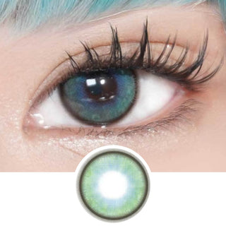 A close-up of a person's eye with EyeCandys Powerglow Turquoise Green contact lenses, teal-green lenses by EyeCandys, light blue hair, long lashes, and shimmery makeup. Below the eye is an enlarged lens image highlighting moisture retention.