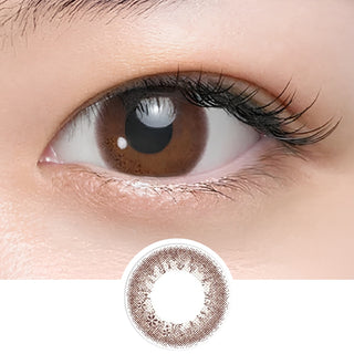 Close-up of eye wearing EyeCandys Seed Coffret Sweetie Make Brown (10pk) prescription colored contact lens with lens design shown below, warm brown two-tone gradient with pink undertone and delicate floral pattern, glossy Korean daily disposable colored contacts for doe eyes