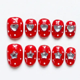 Ten EyeCandys Spot the Difference Press-On Nails in red with white polka dots, each handmade with a clear heart or star gem at the center, arranged neatly on a white background for a fun salon gel manicure.