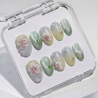Short oval press on nails EyeCandys Spring Fling with sage to cream ombre gradient, cherry blossom nail art, and crystal center details.