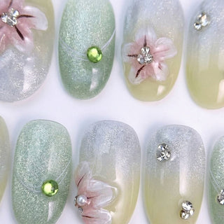 EyeCandys Spring Fling press on nails featuring sage green to cream gradient with iridescent shimmer, 3D pink cherry blossoms, and crystal accents.