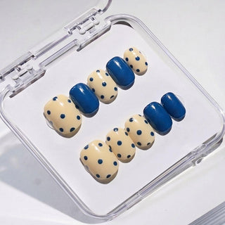 EyeCandys Sunny Side Up press on nails featuring butter yellow nails with navy polka dots and alternating solid glossy navy color block design.