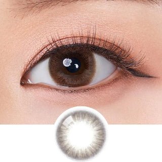 A close-up of a brown eye with long lashes and winged eyeliner, above an image of Olola Swany Pure Choco contact lens by Olola, featuring a dark outer ring and lighter center. Perfect for those seeking non-prescription lenses.